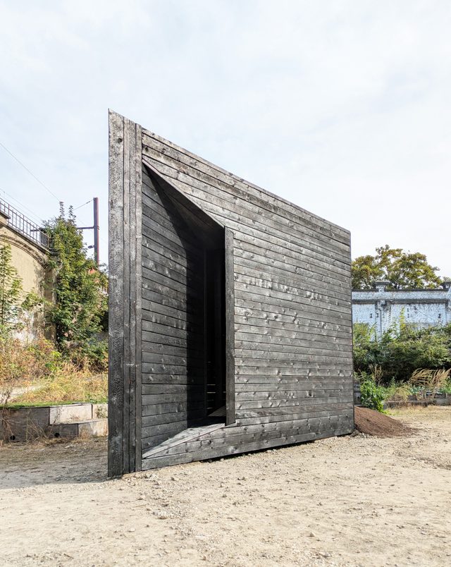 Plough Chapel, a wedge-shaped charred-timber chapel in a courtyard in Anderlecht, Brussels