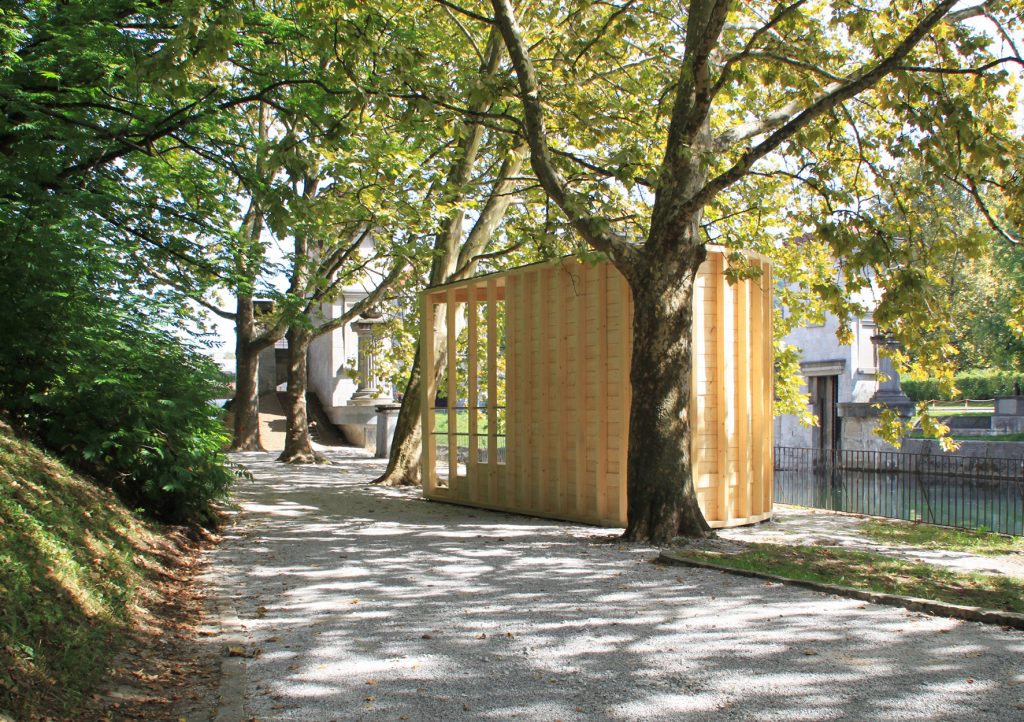 The curved timber pavilion seen from the hill in the riverside park